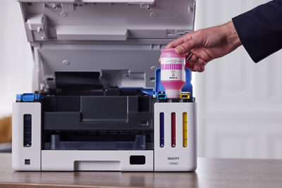 MAXIFY GX6110 - Person Using Ink Bottle to Refill Printer