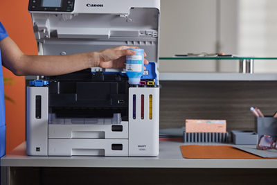 MAXIFY GX7110 - Person Using Ink Bottle to Refill Printer
