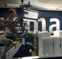 Man controlling a large camera inside a newsroom