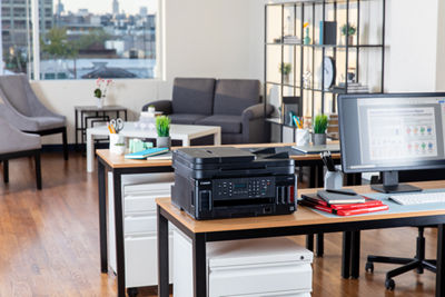 A Canon printer sits on a desktop with other office supplies