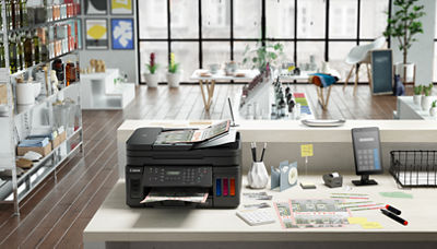 Canon printer on a desk with other office supplies