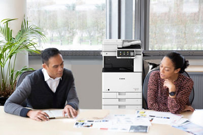 Two individuals discussing papers on a desk
