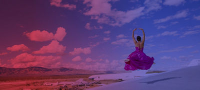 Dancer with mountains and a blue sky filled with clouds in the background