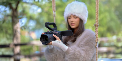 lady in red dress lying on the floor next to ornaments holding a canon camera