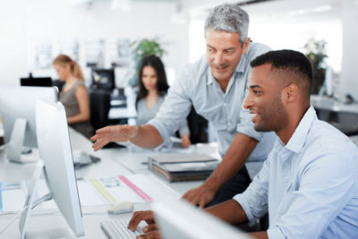 Employees discussing business in front of a desktop computer