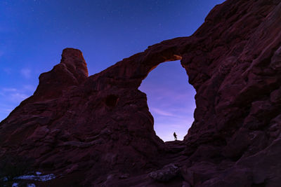 Person Standing on Rock Formation at Night