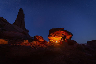 Person In Front of a Fire and Next to a Rock at Night 