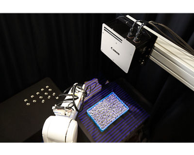 A robotic arm hovering over a bin of small items, an example of automated bin picking.