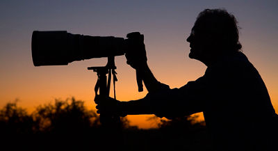 Silhouette of photographer at sunset with telephoto lens