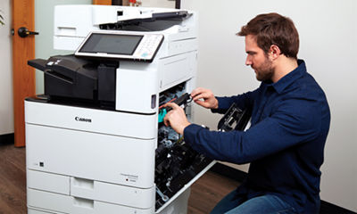 Image of a man working on a Canon printer