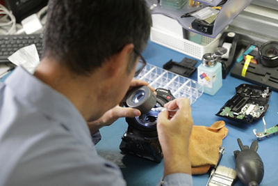 Hands Holding Tool Working on Lens