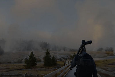 Man walking with a tripod on his shoulder 