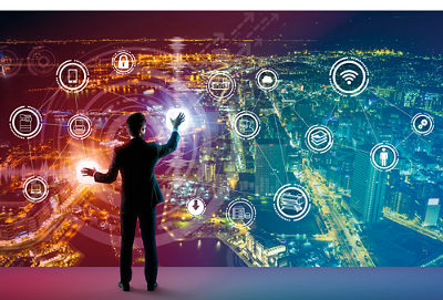 A man in a suit uses what looks like a wall sized interactive display with a colorful city and multiple icons. 