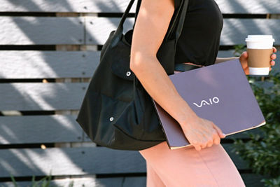 Person Walking with a Laptop and a Coffee