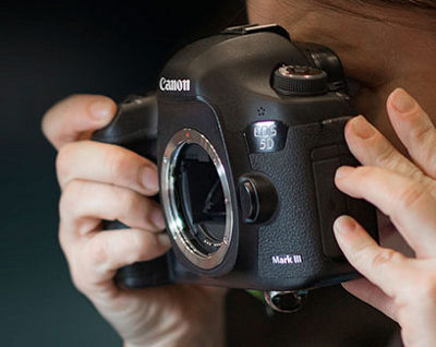 Close-up of hands holding a camera with a red overlay on the image
