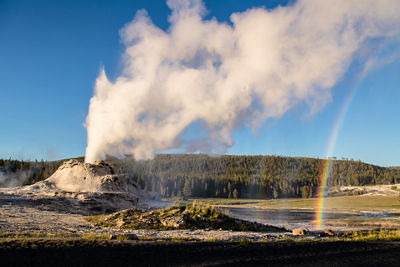 Geyser smoldering beside a rainbow in Yellowstone.