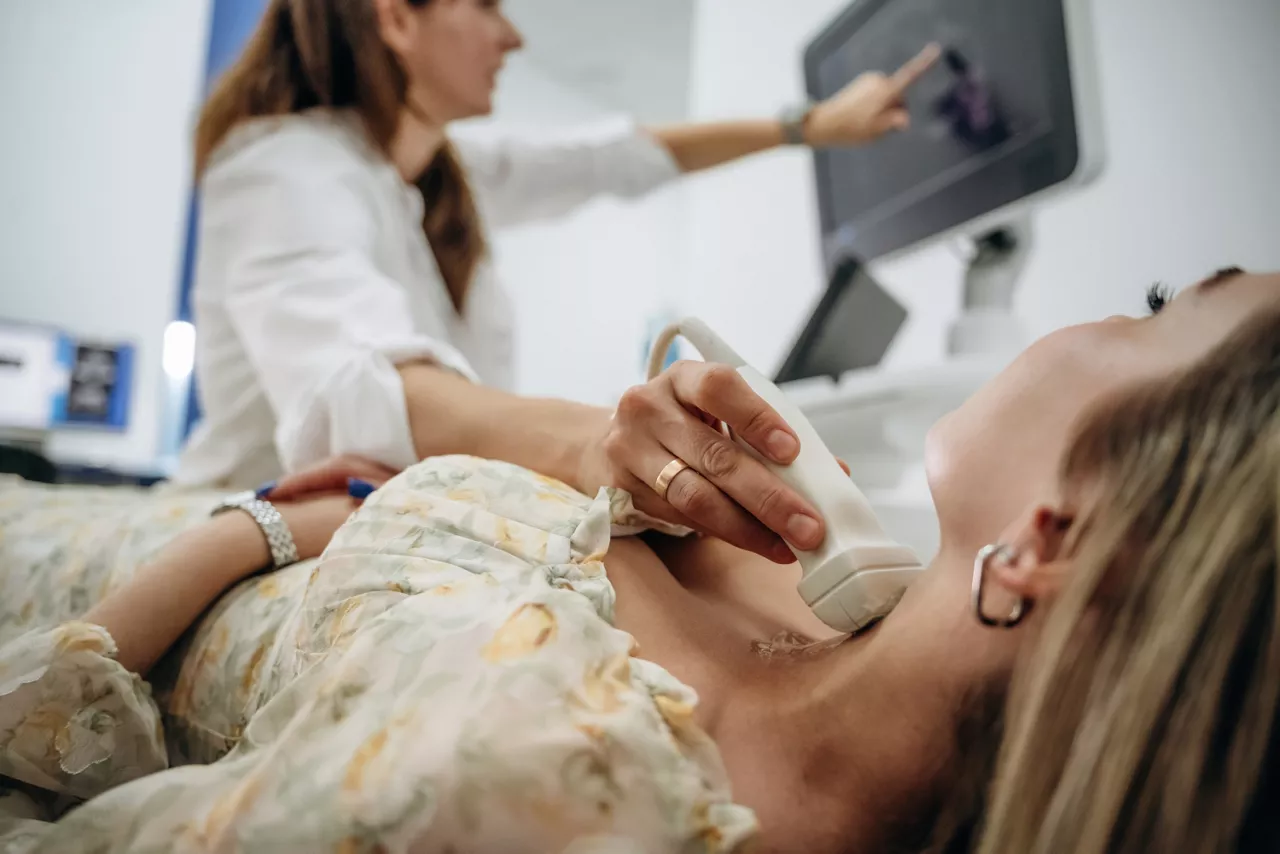 Side view. Woman is lying down and undergoing ultrasonic test of the thyroid gland.
