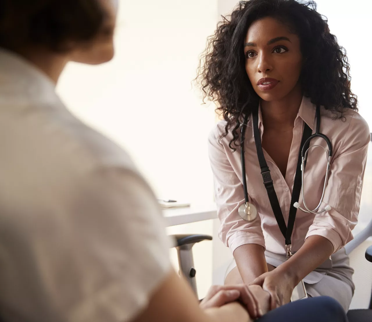 Female Doctor In Office Reassuring Woman Patient And Holding Her Hands