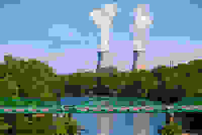 Two cooling towers in the distance with green bridge across waterway