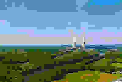 Two cooling towers off in the distance of a blue sky