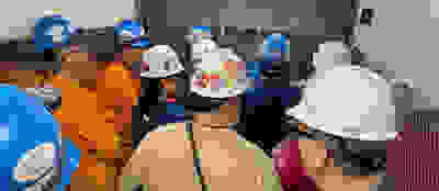 group shot from behind of construction workers wearing hard hats in a freight elevator