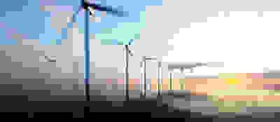 Wind turbines in water with sun in background