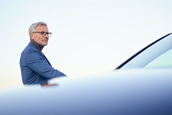 Man stood by car wearing blue