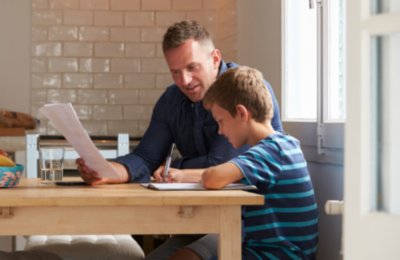 Father and son looking at papers at kitchen table.