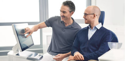 Man in lab coat teaching a student about digital dentures
