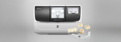 CEREC Primemill device with clear aligner and veneers in foreground.