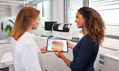 Two dental professionals reviewing a CEREC restoration design on a tablet using DS Core workflow.