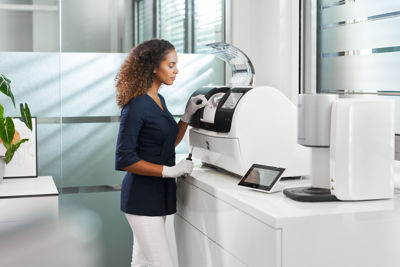 Dental professional operating a CEREC Primemill unit to manufacture ceramic restorations.