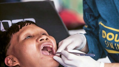 Close-up of a dentist's gloved hands using a metal instrument to check a patient's oral situation. 