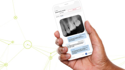 Hand holding smartphone displaying dental X-ray and patient communication app interface