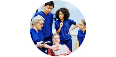 Group of dental professionals discussing a case around a patient model.