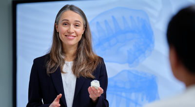 Female presenter explaining dental workflow with a 3D tooth model on screen.