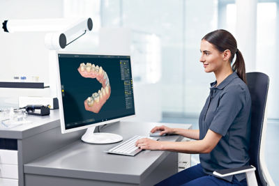 Dental technician designing a 3D dental restoration on a computer with inLab CAD software.