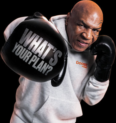 Mike Tyson in a grey hoodie throwing a punch towards the camera, with the words "WHAT'S YOUR PLAN?" written in silver on his black boxing glove.