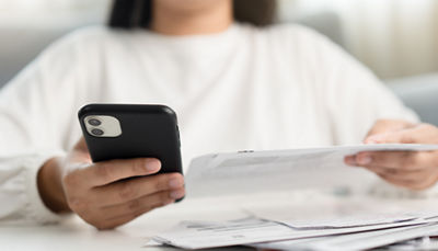 Consumer reviewing cell phone bill and mobile data settings on a smartphone