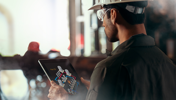 Factory worker using tablet to observe a piece of equipment