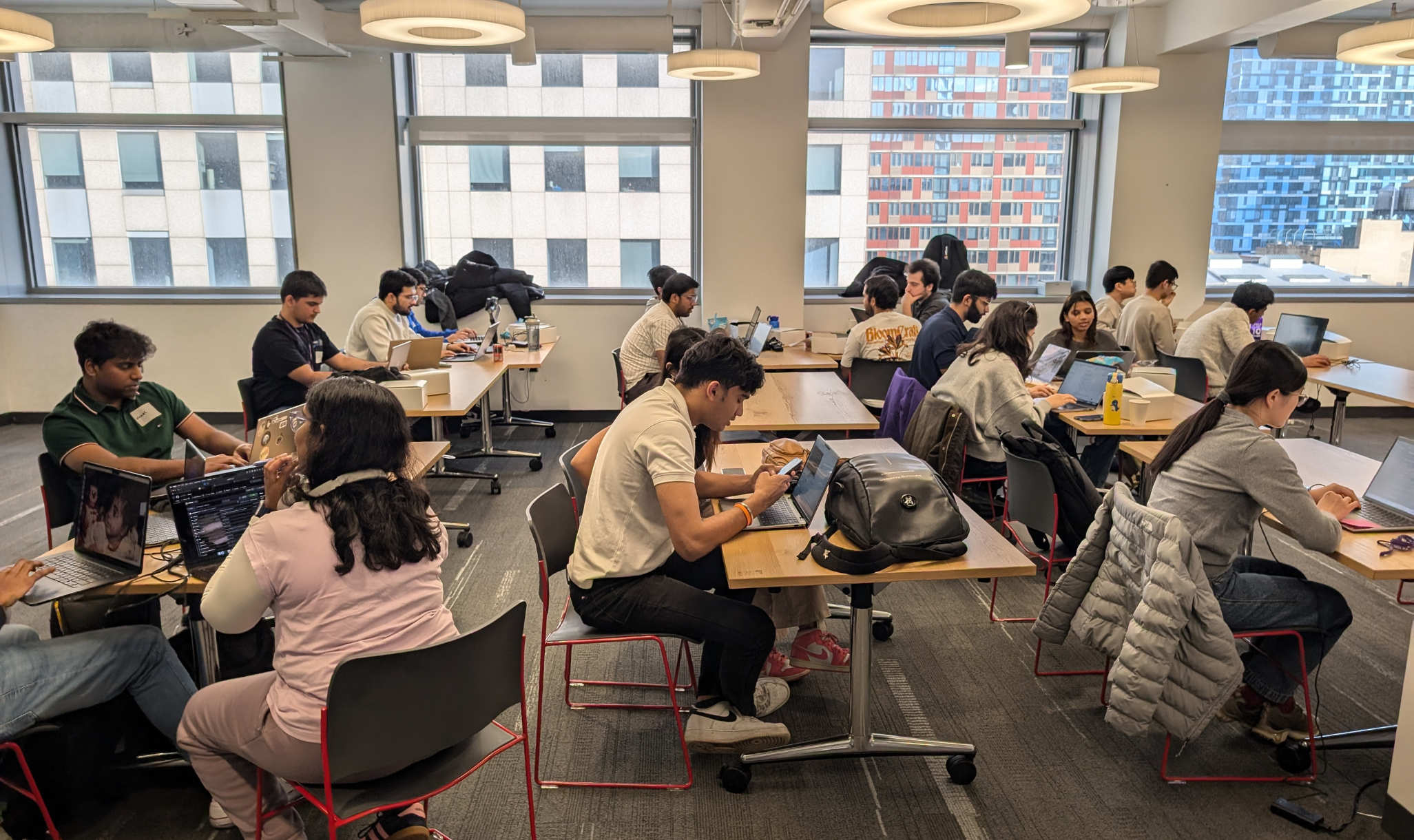 A group of people sitting at tables in a room with windows