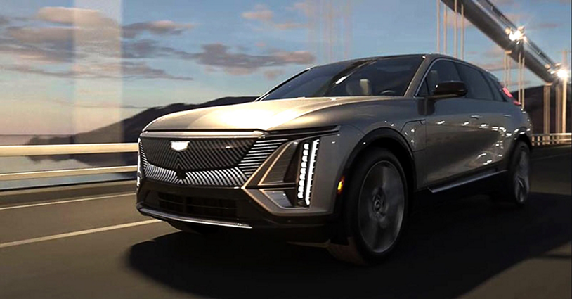 Cadillac LYRIQ cruising on a bridge by a body of water.