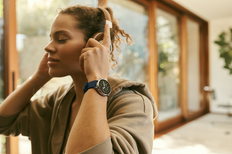 Brunette woman wearing over-the-ear headphones and smartwatch.