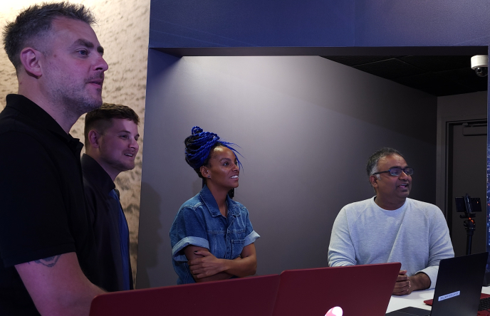 Paul Smith and Kevin Breeze (left) watch alongside Lucy Hedges (center) as Sriram Dixit (right) demos the generative AI capabilities of Snapdragon X Elite. 