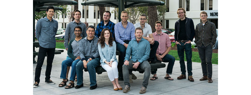 Twelve people seated and standing around a metal structure outdoors at Silk Labs