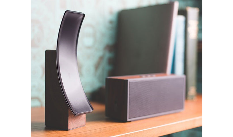 TSense device, a secure camera and hub for use in the home, is shown on a shelf next to a portable speaker.