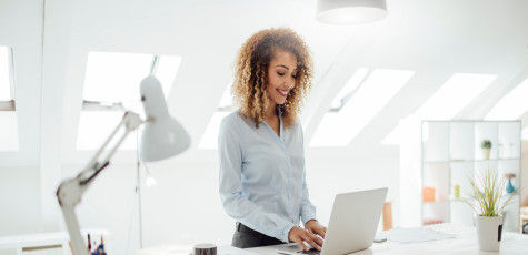 A woman, at her desk, working on her laptop.