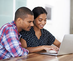 Shot of a young couple sitting at their dining table using a laptop