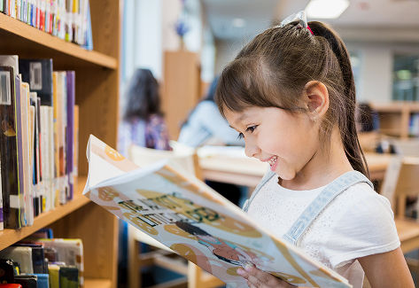 Female child reading in school library