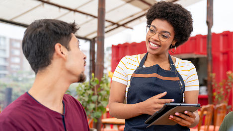 People at outside market reviewing a tablet